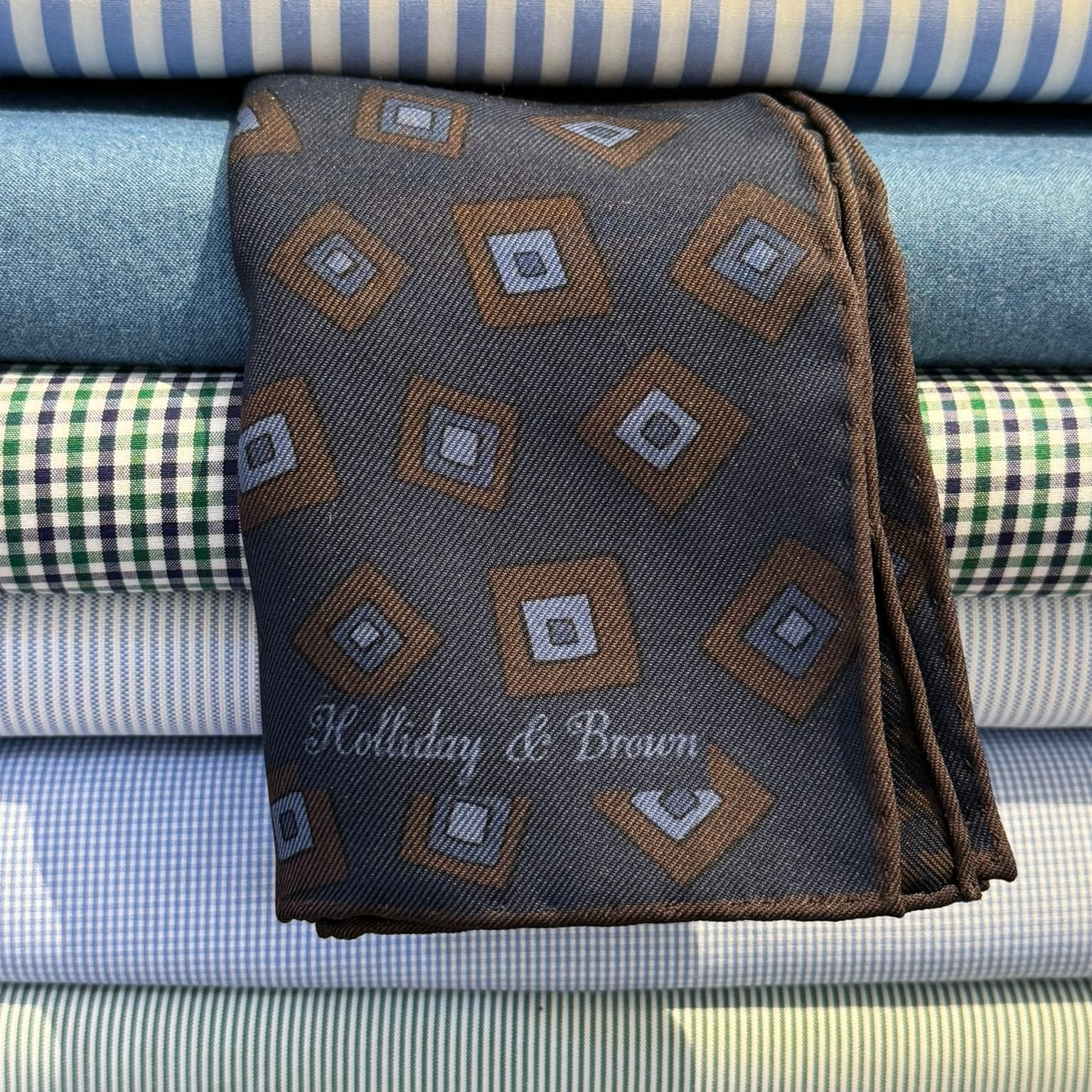 Holliday &amp; Brown
Hand-rolled&nbsp;&nbsp;
Holliday &amp; Brown for Cruciani &amp; Bella
100% Silk
Navy Blue, Brown and Light Blue
Double Faces
Motif&nbsp; Pocket Square
Handmade in Italy

32 cm X 32 cm